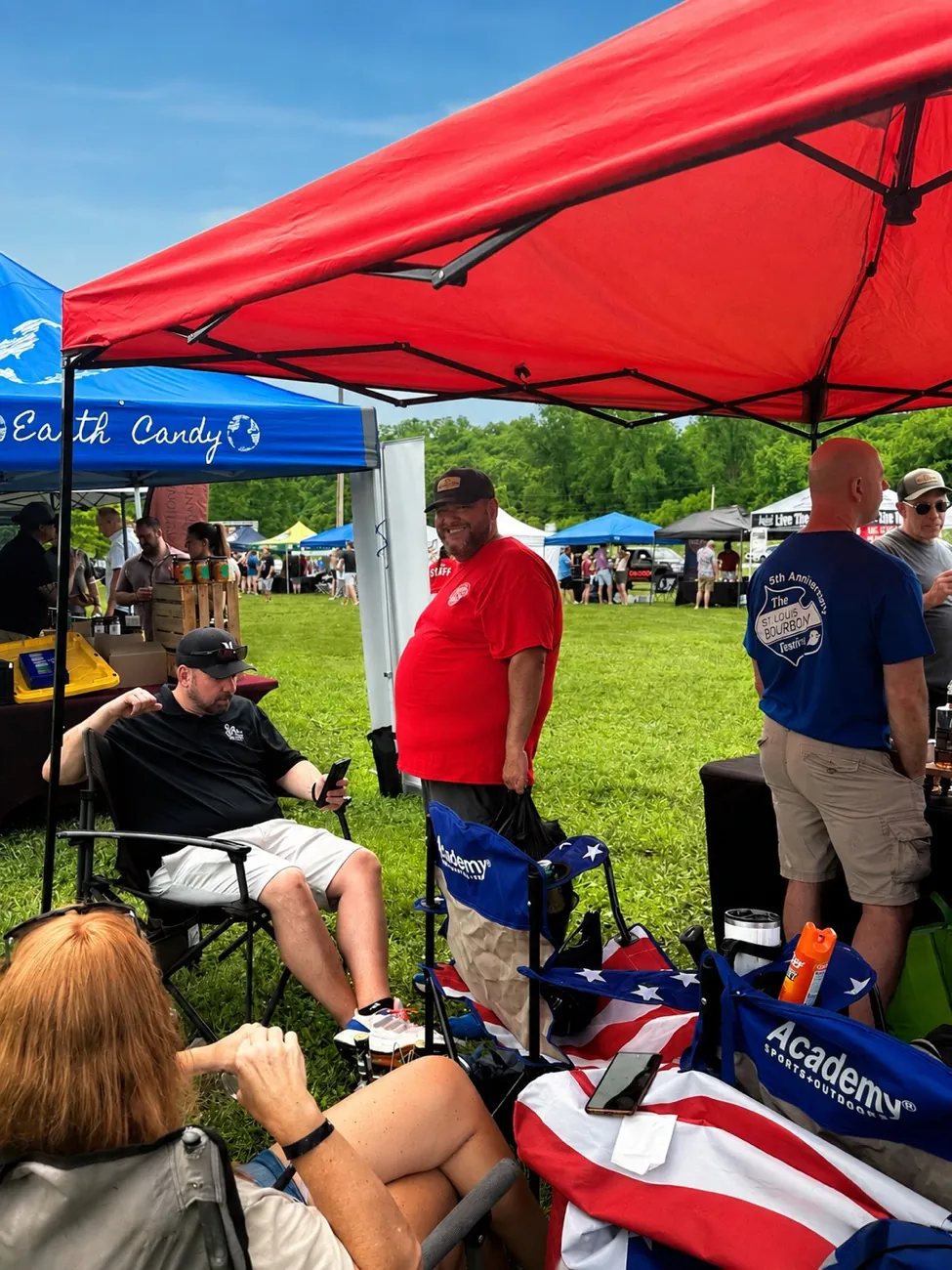 Guests gathering under a red vendor tent at the 1st Annual MO Spirit Festival